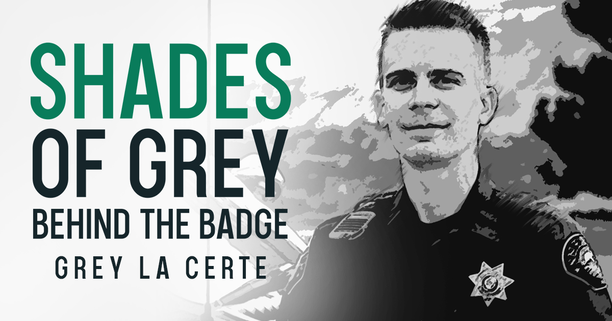 A black and white image of a police officer named Grey La Certe standing with confidence, wearing a badge and uniform, as the centerpiece of the 'Shades of Grey - Behind the Badge' series.